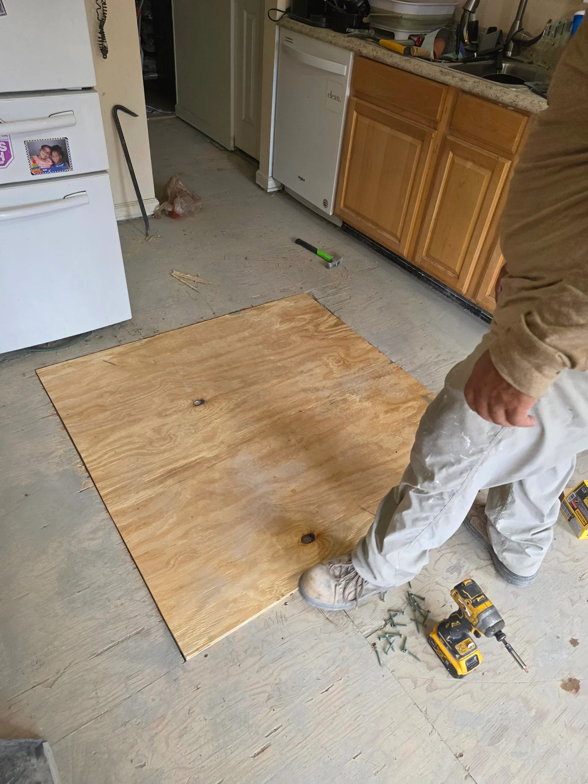 FIXO installer laying plywood underlayment over a kitchen subfloor