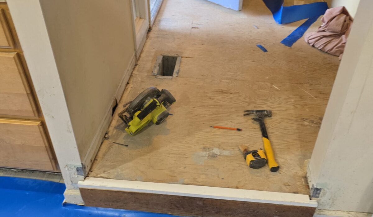 Plywood subfloor prepped with a moisture barrier before plank flooring is laid