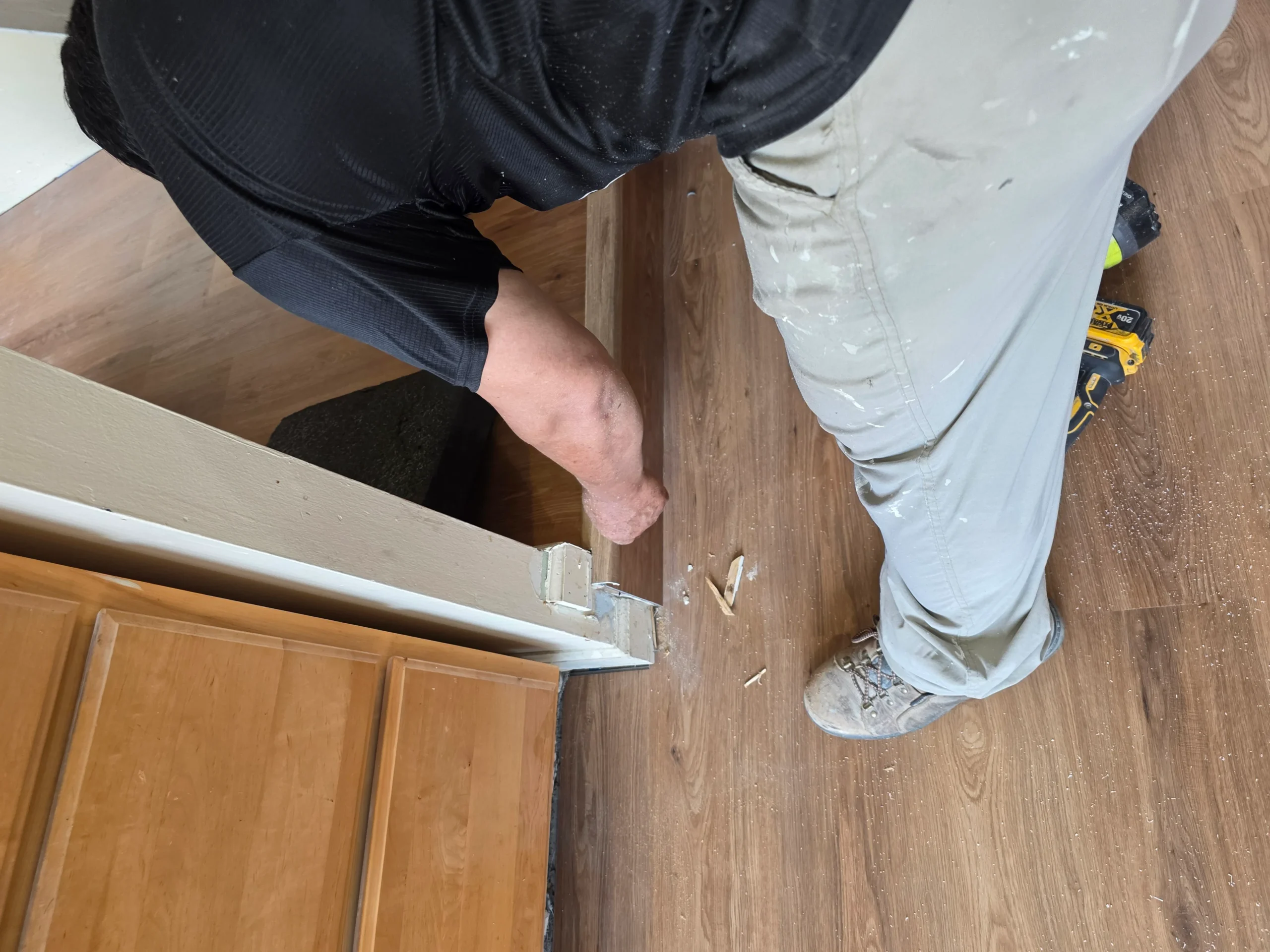 FIXO installer fitting baseboard trim over newly installed plank flooring