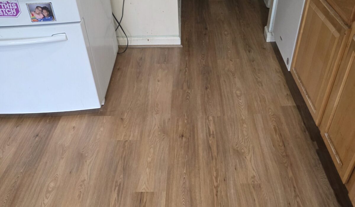 Finished luxury vinyl plank flooring running through a kitchen and hallway