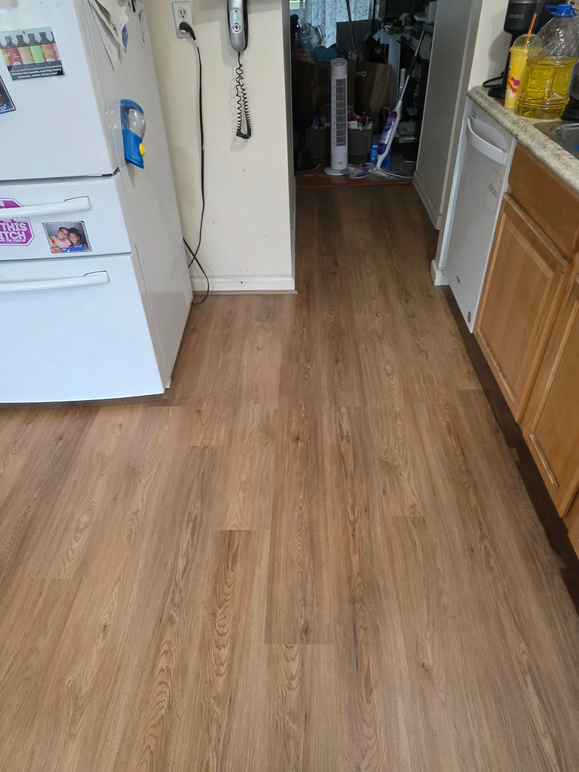 Finished plank flooring running through a kitchen and hallway