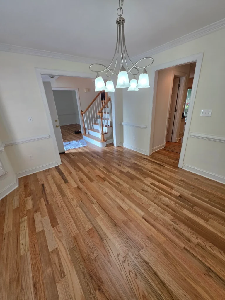 Finished hardwood flooring in a dining room under a chandelier