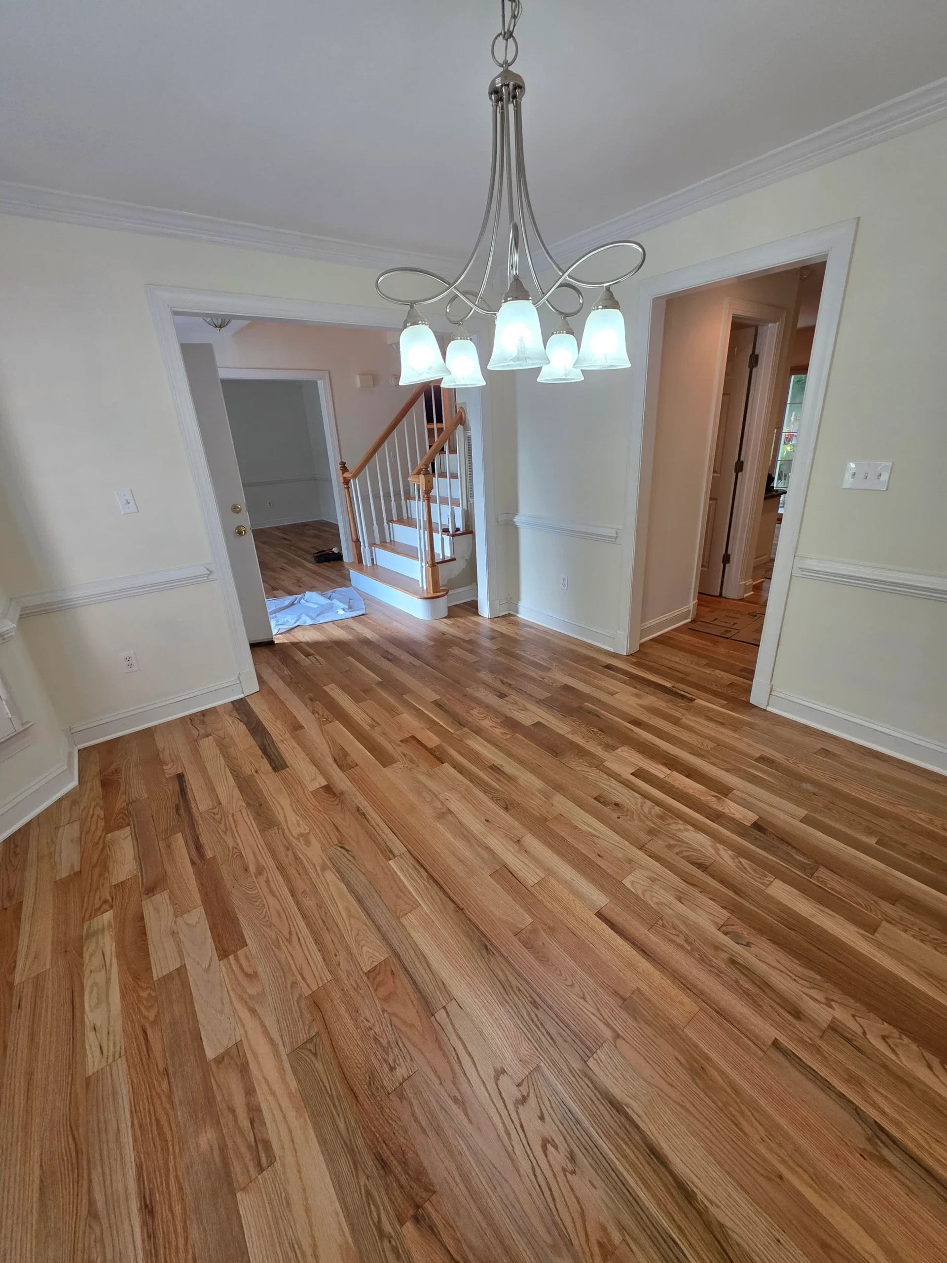 Finished hardwood flooring in a dining room under a chandelier