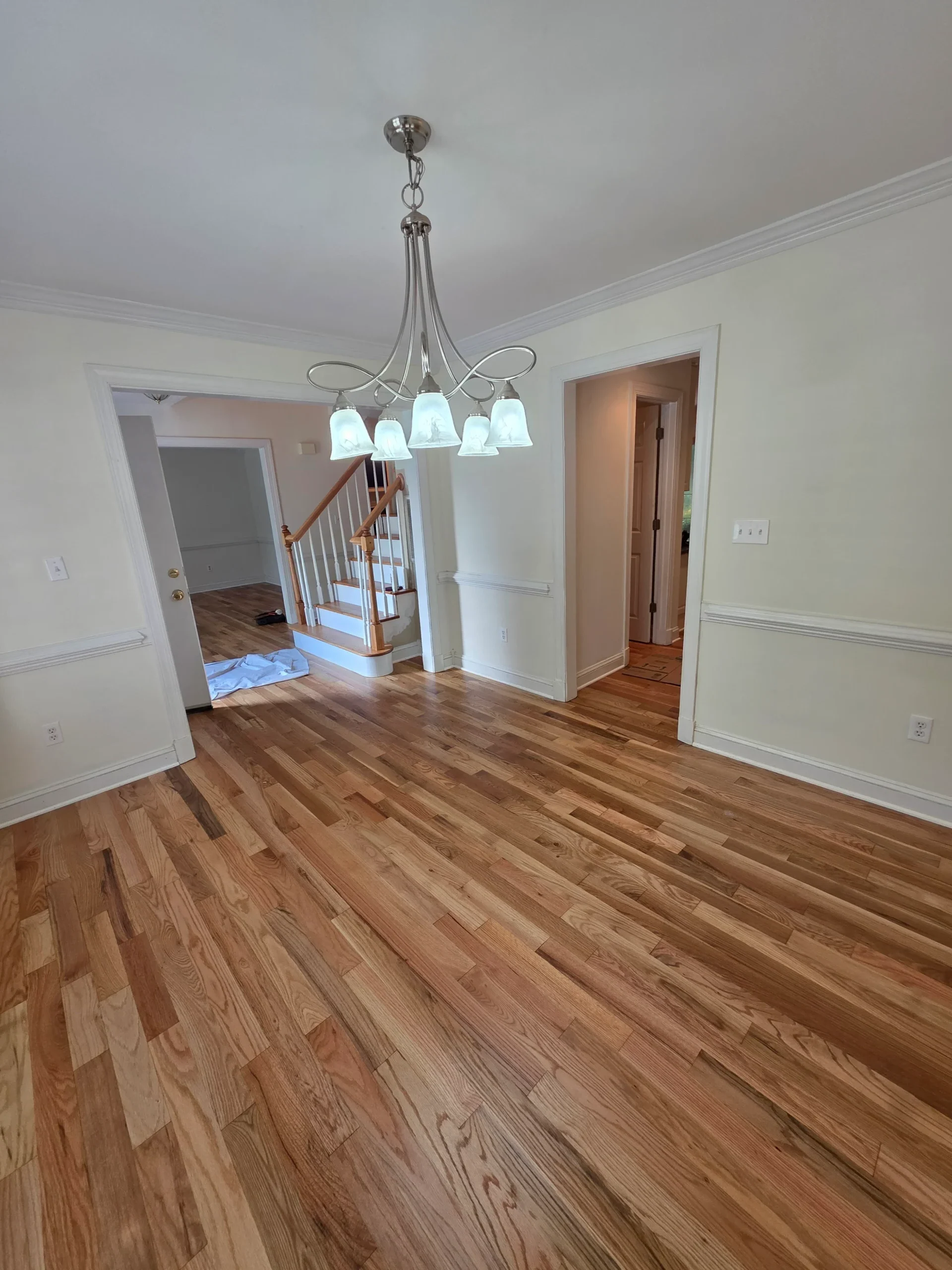 Finished hardwood dining room floor with the staircase beyond