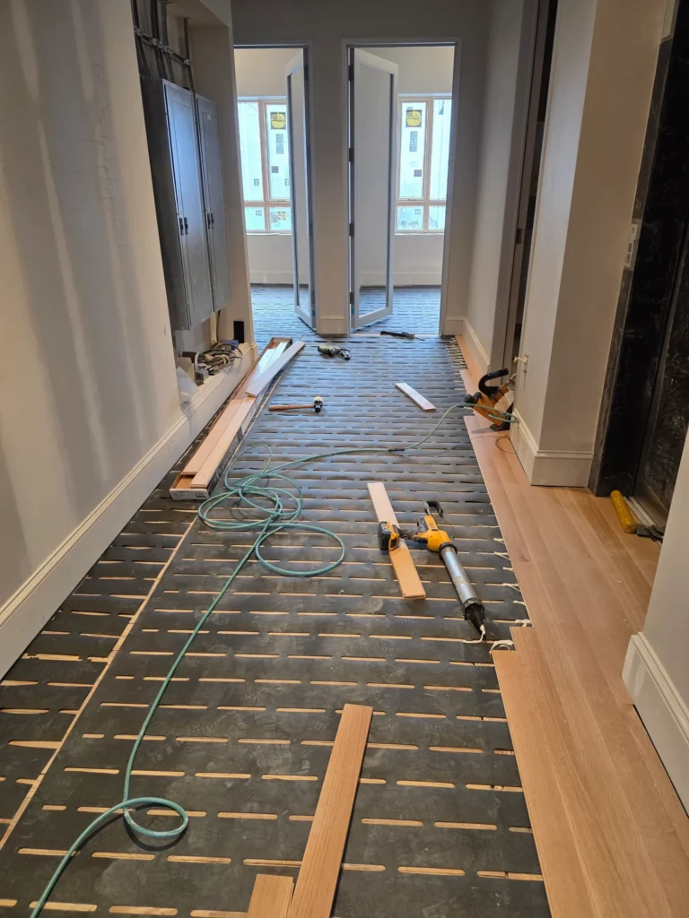 Underlayment laid across a hallway with planks staged ready to install