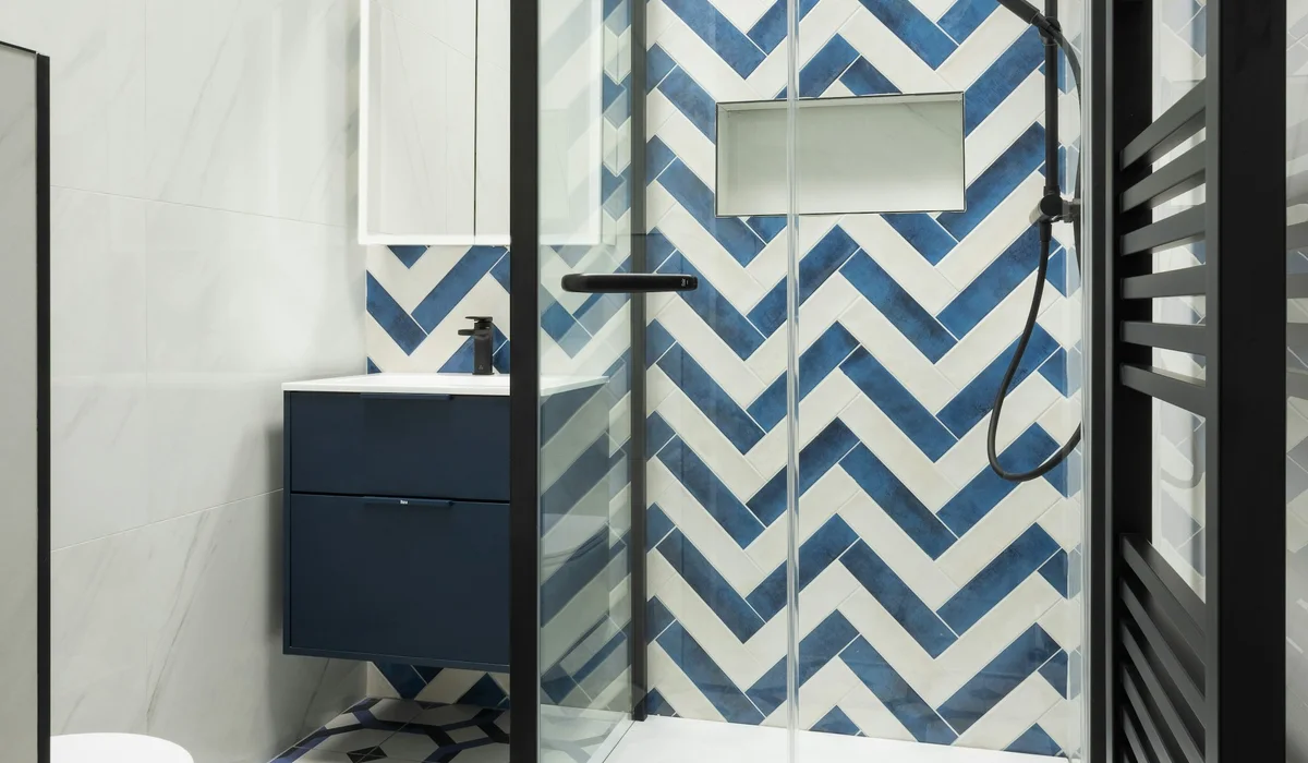 Modern bathroom with blue chevron wall tile and a geometric patterned tile floor