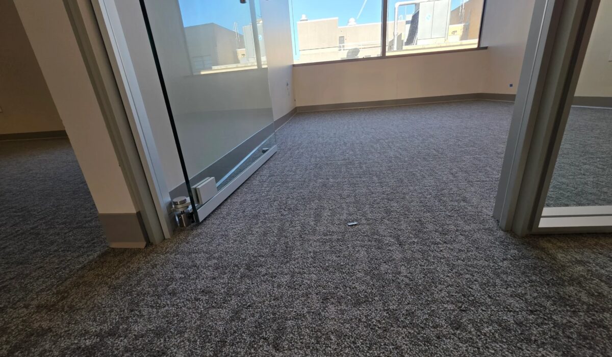 Corner office finished with charcoal carpet tile and glass partitions