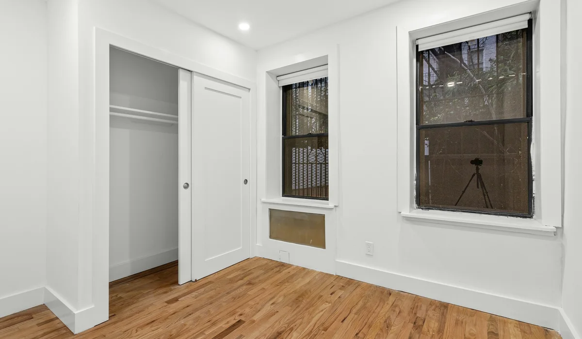 Empty room with white walls and wood floors, where baseboard and trim add to the installed cost