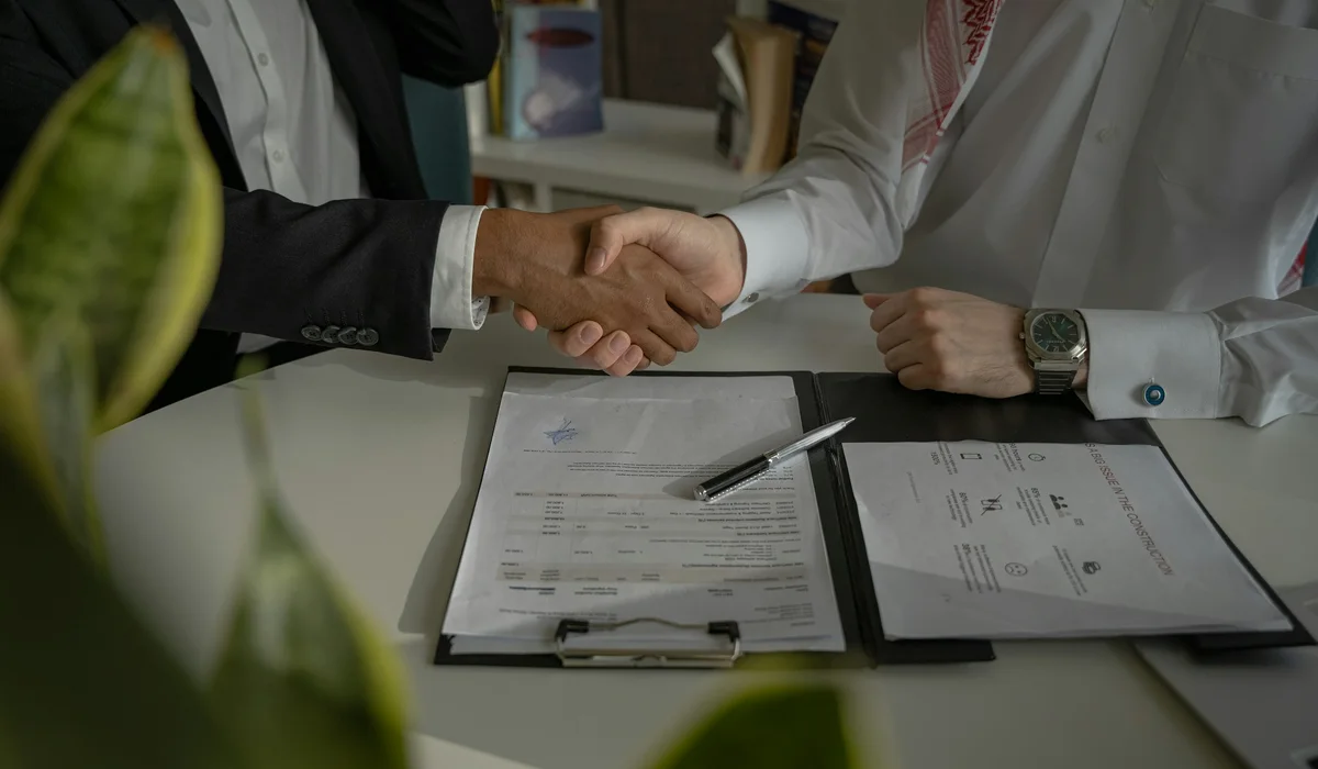 Handshake over a signed contract on a desk