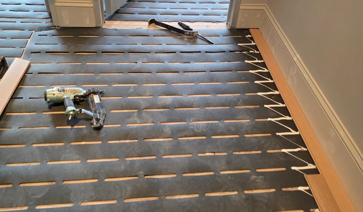 Hardwood boards racked out across the subfloor before nailing