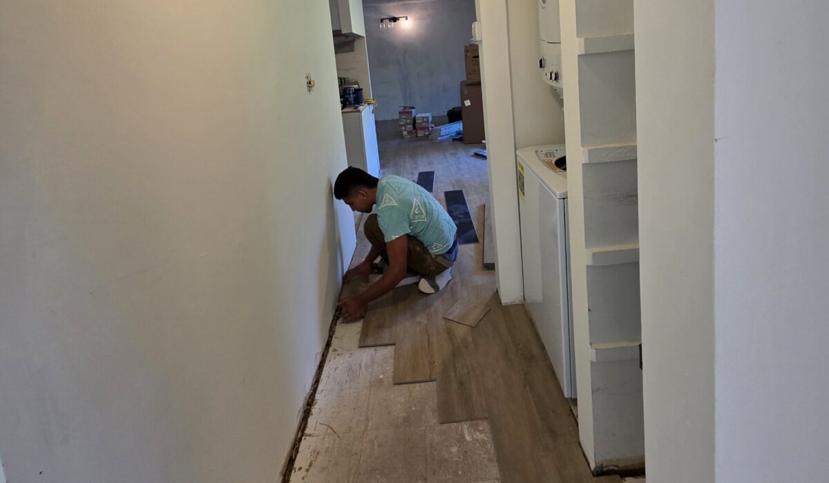 Installer fitting new flooring along a narrow upstairs hallway