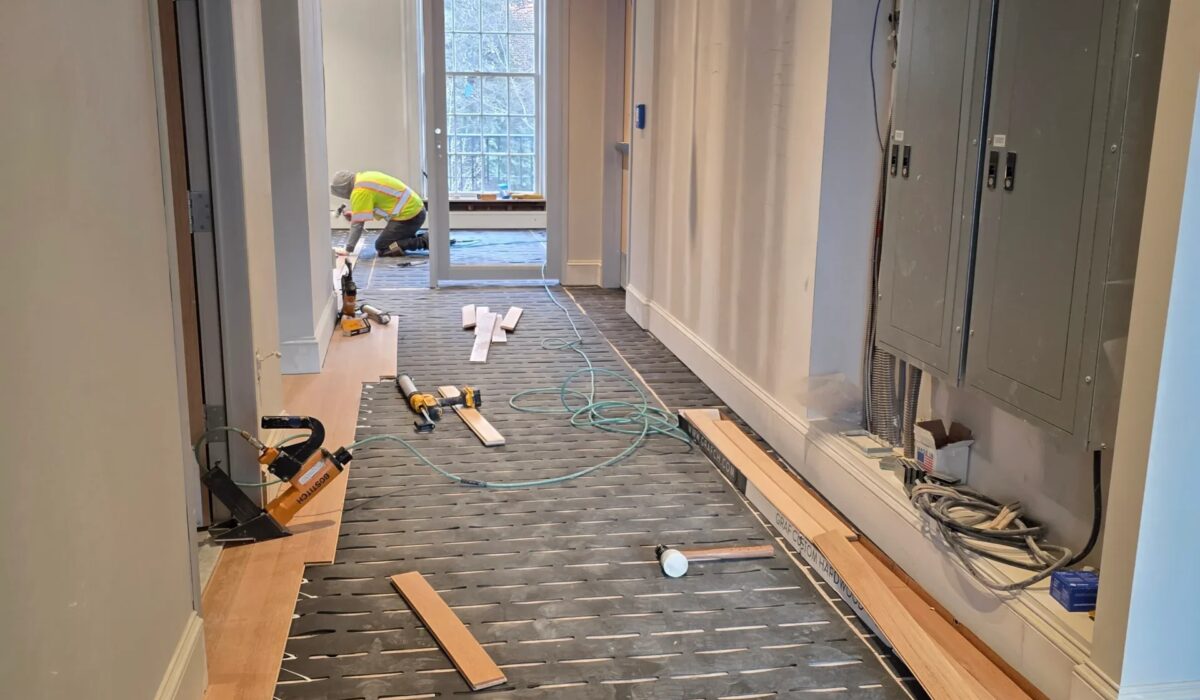 Planks and underlayment staged down a long hallway before installation