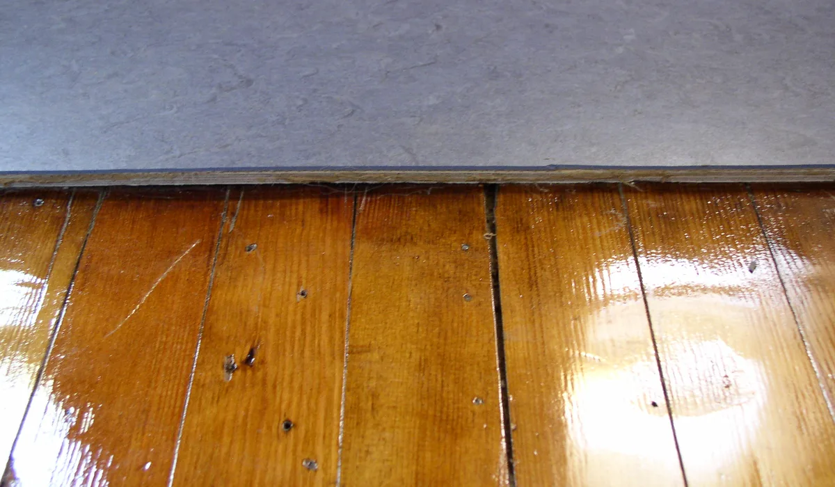 Edge of a linoleum floor laid over plywood underlayment, the base most linoleum flooring installation needs on a wood subfloor