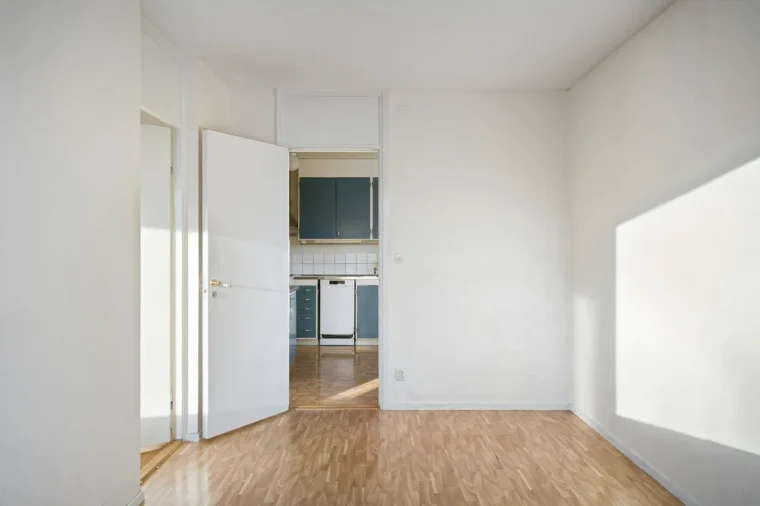 Empty room with white walls and a light plank floor, ready to measure for an LVP flooring installation cost calculator