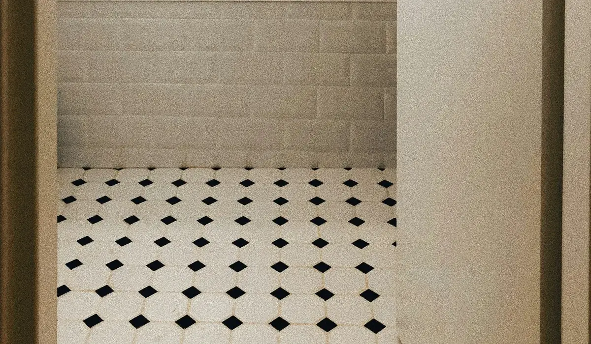 Black and white octagon-and-dot mosaic floor tile in a small bathroom with a subway tile tub surround