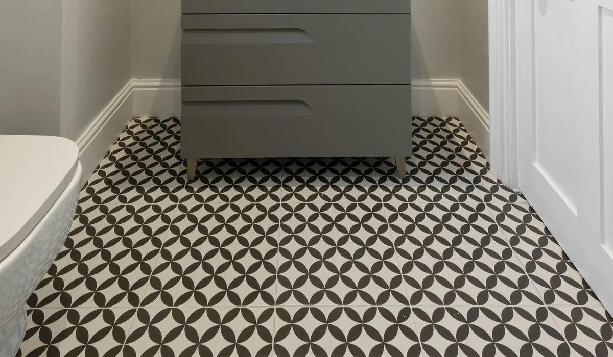 Black and white patterned floor tile in a small bathroom with a grey floating vanity