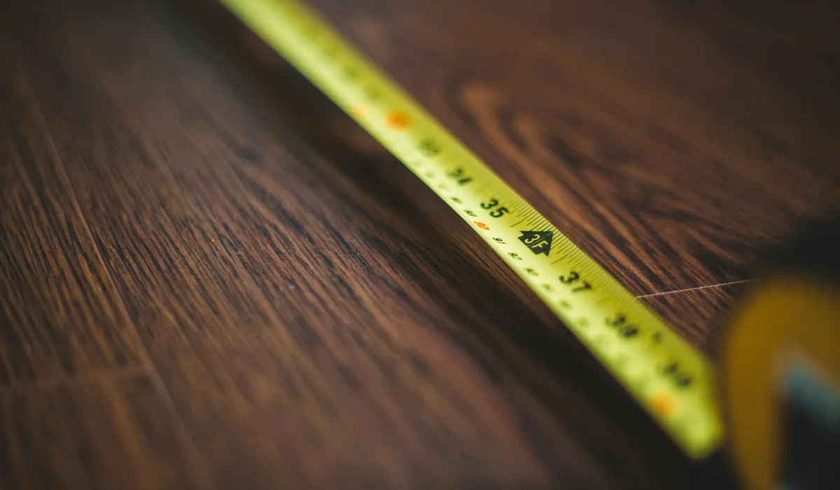 Tape measure on a wood look floor for checking room size and expansion gaps