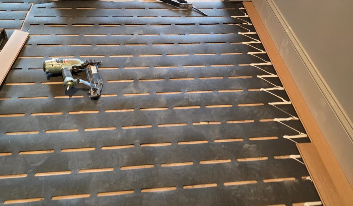 Underlayment strips down and the first planks staged at a doorway