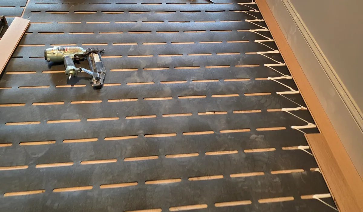 Underlayment laid across a prepared hallway with planks staged at the doorway