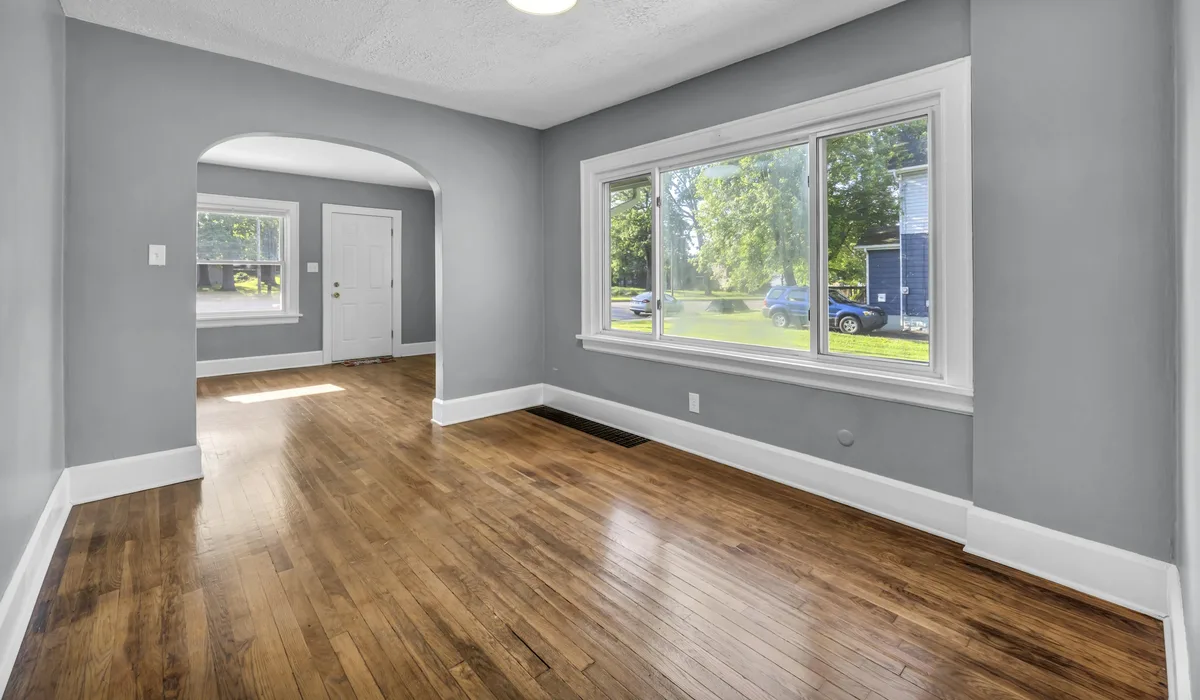 Empty room with a warm mid-tone oak-look floor, grey walls and white baseboards