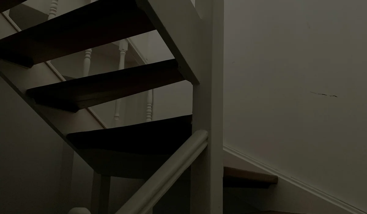 White staircase with a wooden handrail running the length of the flight