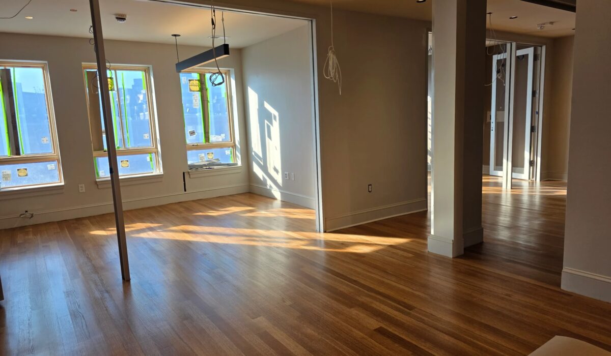 Wide-plank engineered hardwood installation in a bright open room with tall windows