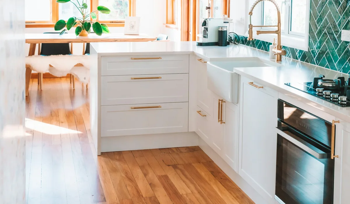 White kitchen with a warm oak-look plank floor and green tile backsplash